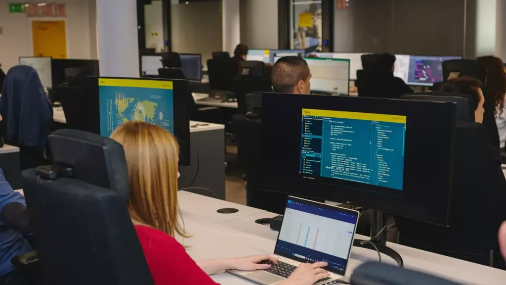 Profesionales trabajando con ordenadores en una oficina tecnológica.