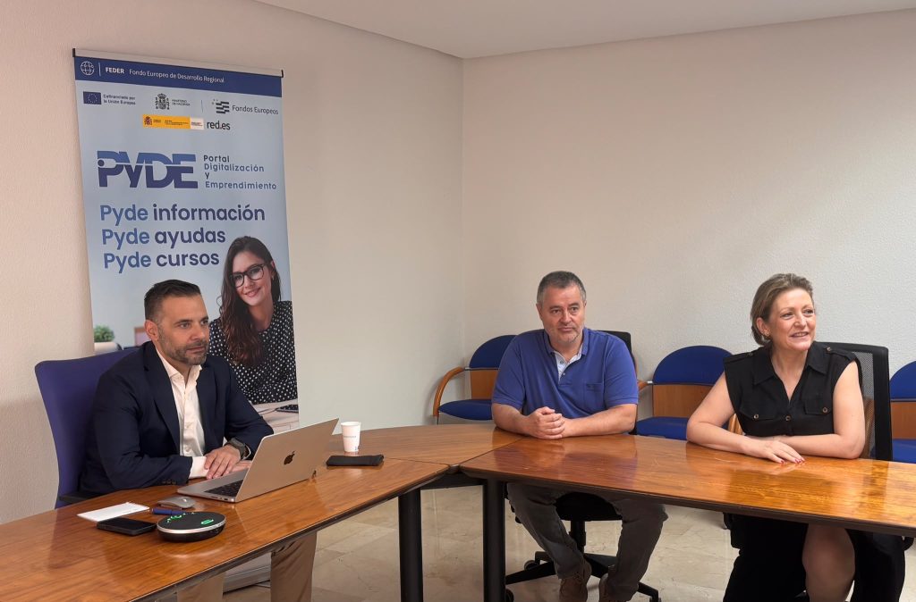 Personas reunidas en una sala de reuniones siguiendo una formación online en una pantalla.